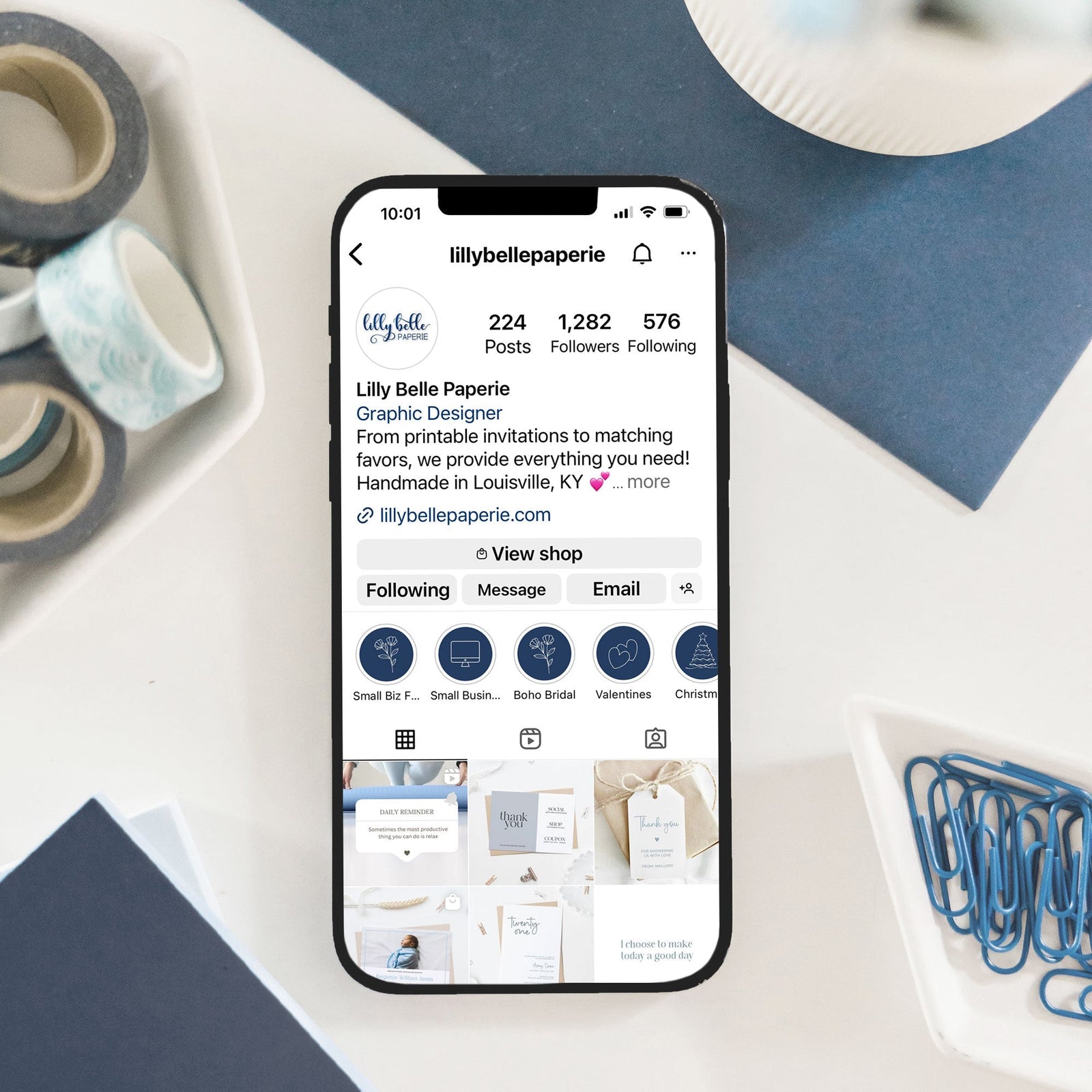 iPhone displaying Lilly Belle Paperie's Instagram Social Media Account with desk decorations along the picture's edge